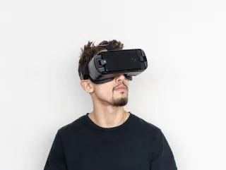 A stock photo of a man wearing a VR headset against a white background.