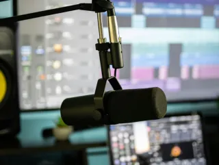 A stock photo of a podcast microphone in a recording studio.