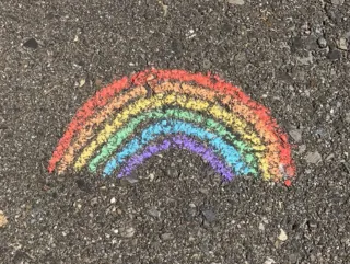 An image of a rainbow drawn in chalk on concrete.