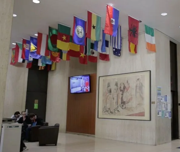 Many nations' flags depicted hanging from the ceiling in the lobby area of Columbia's School of International and Public Affairs