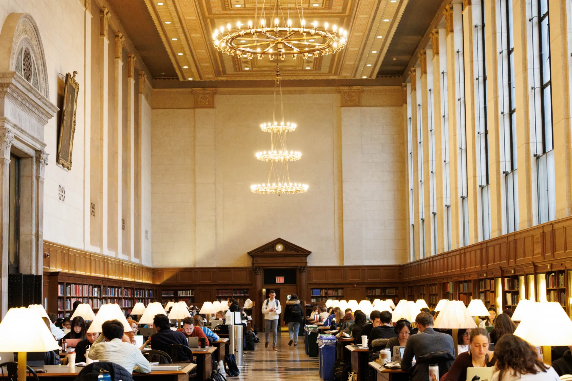 Students studying in a brightly lit Butler Library reading room.