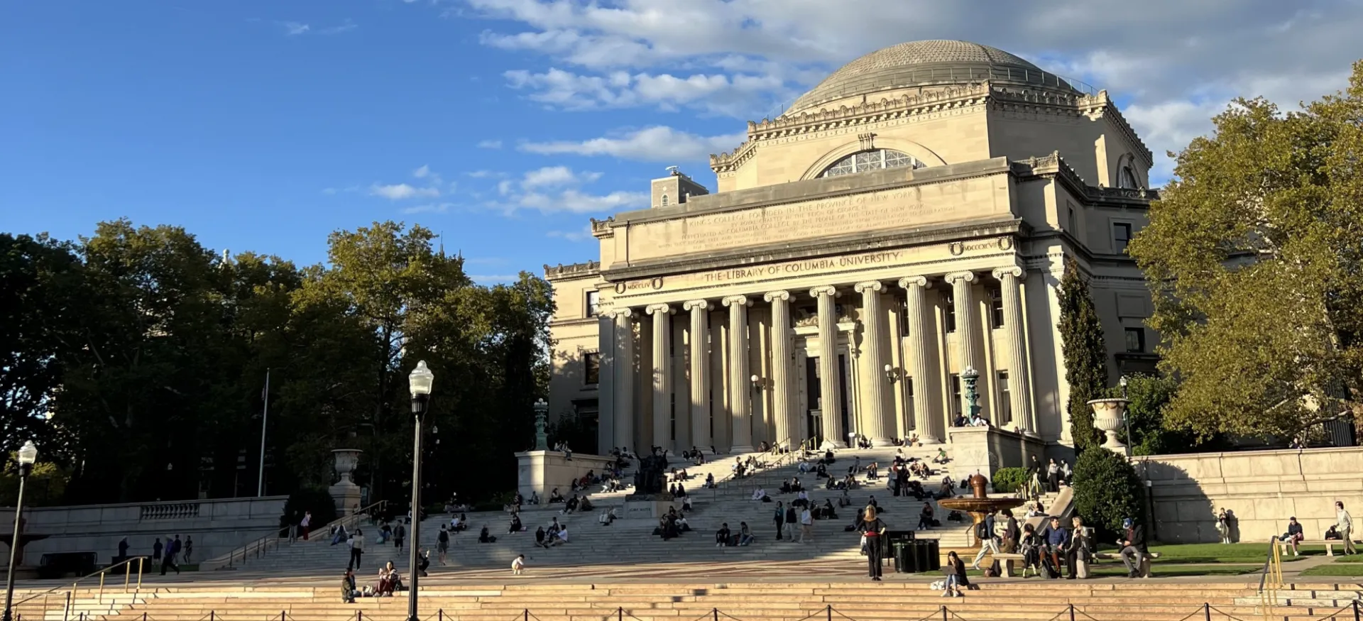 Low Library at Columbia during golden hour, with many students sitting on the steps.