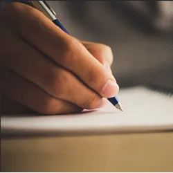 Close of up hand holding pen, writing on paper