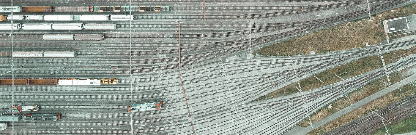 Aerial view of trains in a trainyard going from many tracks on the left to few tracks on the right. Image by Patrick Federi on Unsplash.