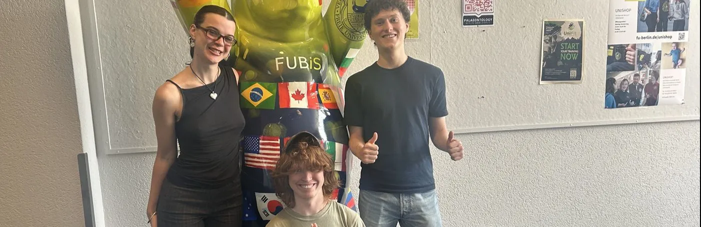 Several students stand in front of the FUBiS-branded (Freie Universität International Summer and Winter Program) Buddy Bear, smiling.