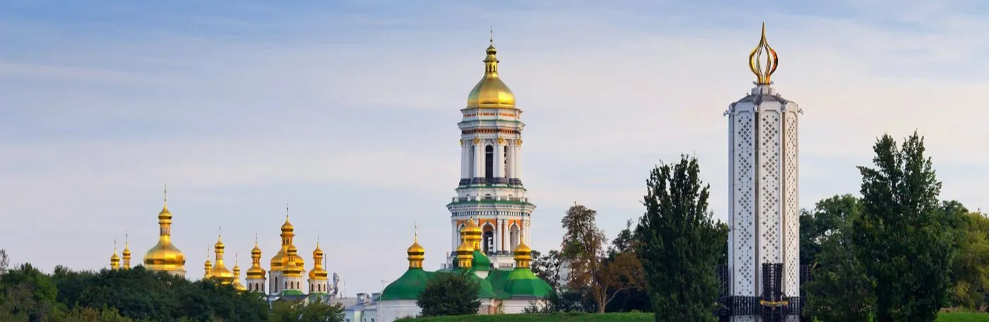 Panoramic view of the golden domes and bell tower of the Kyiv Pechersk Lavra monastery complex next to the Holodomor Memorial candle tower in Kyiv, Ukraine.