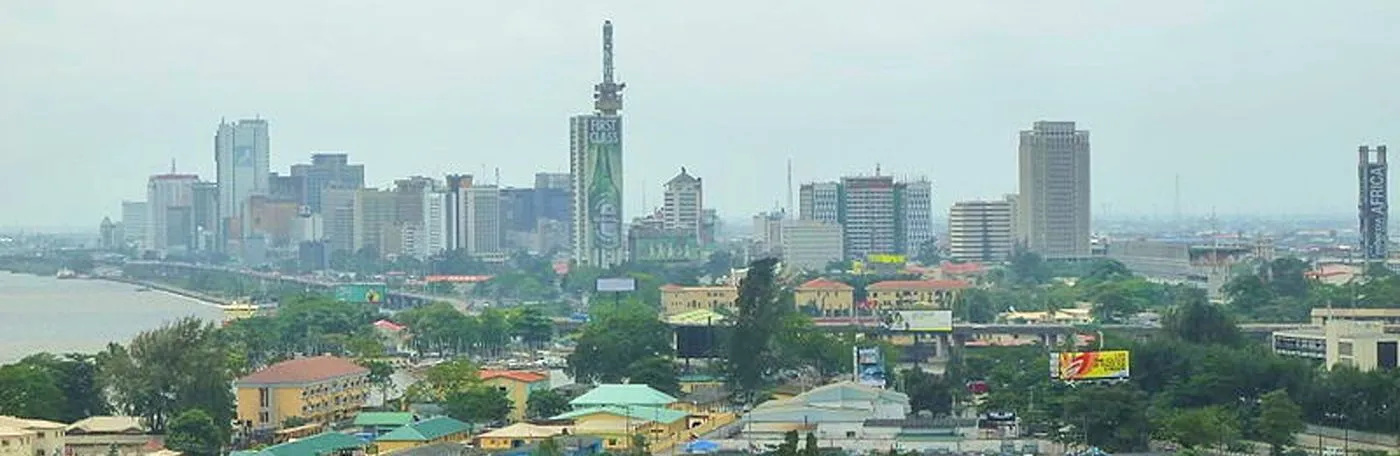 Panoramic view of the Lagos, Nigeria city skyline along the waterfront under an overcast sky.