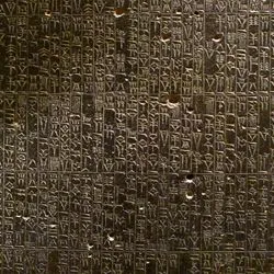 A background of Akkadian cuneiform script carved into dark stone.