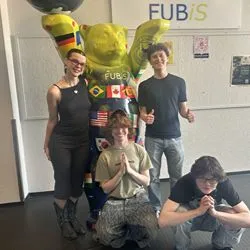 Several students stand in front of the FUBiS-branded (Freie Universität International Summer and Winter Program) Buddy Bear, smiling.