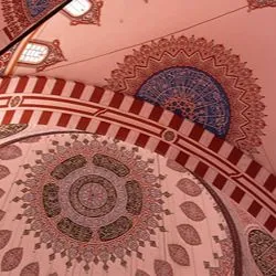 Low-angle panoramic view looking up at the ornately decorated domes and arches of an Ottoman-style mosque, featuring intricate Arabic calligraphy and red-and-white striped patterns.