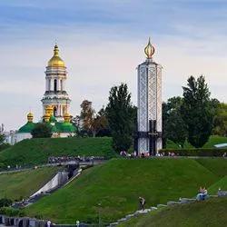 Panoramic view of the golden domes and bell tower of the Kyiv Pechersk Lavra monastery complex next to the Holodomor Memorial candle tower in Kyiv, Ukraine.