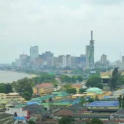 Panoramic view of the Lagos, Nigeria city skyline along the waterfront under an overcast sky.